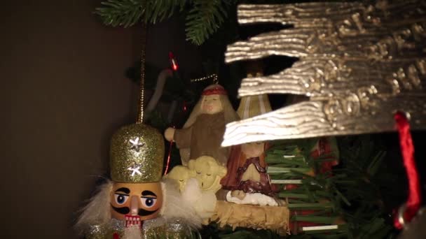 金属のクリスマスツリーの装飾に向かって押すと キリストはこれのために生まれた バックグラウンドでナッツクラッカー マネージャーの装飾を明らかにしました — ストック動画