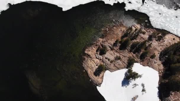 Aerial Top Lago Parcialmente Congelado Sereno Nieve Parcheada Roca Pinos — Vídeos de Stock