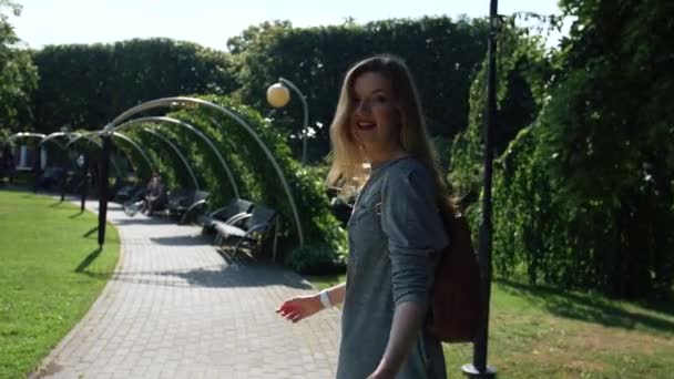 美しい女性は公園で彼女に従うように私たちを招待しています 彼女は私たちに町を見せてうれしい スローモーション ラトビアのジュラ紀 — ストック動画