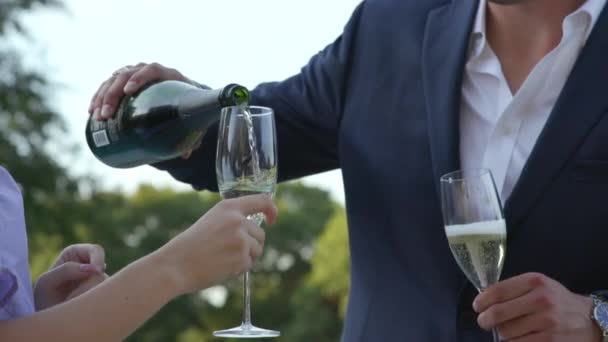 遅い動きにシャンパンのボトルを注ぐことによって若いカップルが祝う — ストック動画