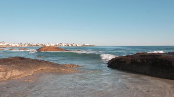 Utsikt Över Havet Vågor Bryta Stenar Förgrunden Med Hus Fjärran — Stockvideo