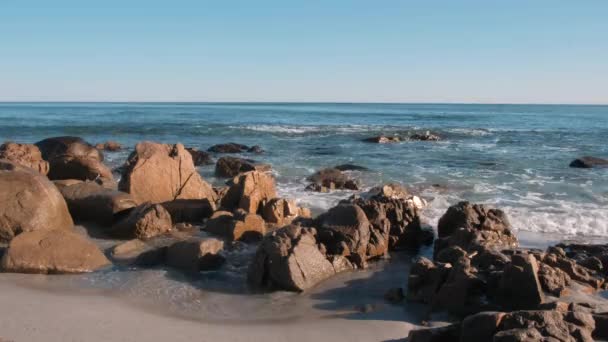 手前に岩があるビーチで波がクラッシュ — ストック動画