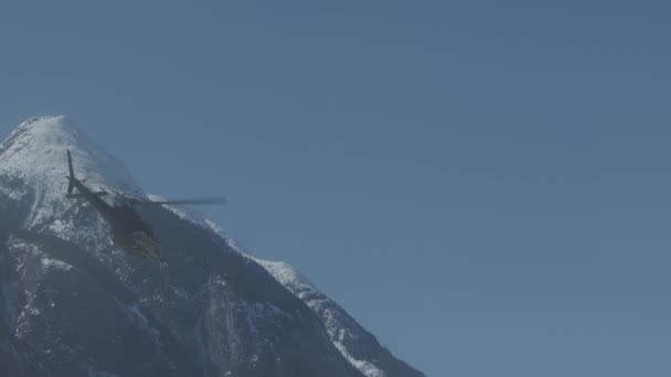 Blue Helicopter Vliegen Weg Door Besneeuwde Bergen Slow Motion Beelden — Stockvideo