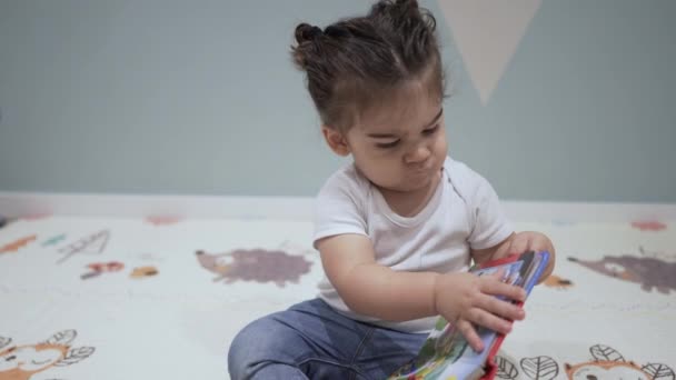 Ребенок Сидящий Полу Вращает Страницы Иллюстрированной Книги Детей Любопытно Глядя — стоковое видео