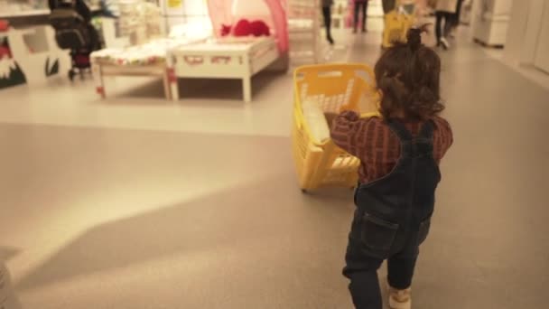 西班牙宜家一年大的幼儿推送黄色购物篮在宜家里面 随后的射击 — 图库视频影像