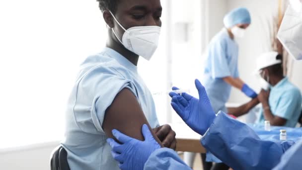 Sykepleier Gir Covid Vaksine Venstre Arm Mot Svart Mann Iført – stockvideo