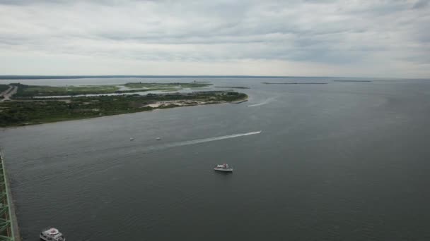 纽约长岛上的大南湾的水面上空有一声高射炮 无人驾驶相机向陆地飞去 在阴天飞越一座桥和一艘抛锚船 — 图库视频影像