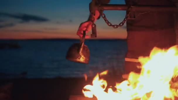 Man Hanging Kettle Fireplace Sea Dusk Travel Equipment Camping Fire — Stock Video