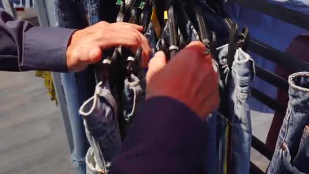 Young Man Choosing Jeans Hung Clothes Rack Mall — Stock Video