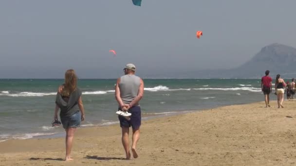 Midden Leeftijd Koppel Wandelen Zandstrand Met Kitesurfers Achtergrond Breed Schot — Stockvideo