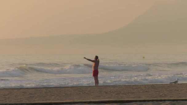 Людина Пляжі Робить Розтягування Вправ Світанку Широкий Постріл — стокове відео
