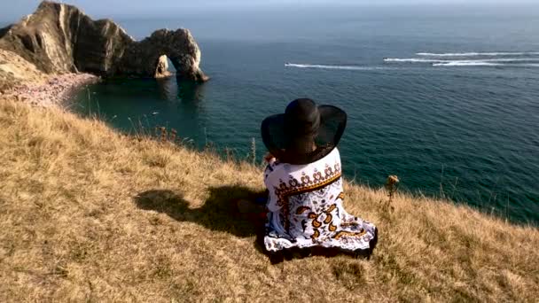 女は崖の上に座って4Kスローモーション — ストック動画
