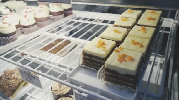パン屋のディスプレイにニンジンケーキと赤いベルベットのカップケーキのおいしい正方形 — ストック動画