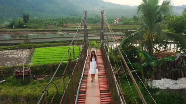 菲律宾南部Leyte的一位孤女赤脚行走在狭窄的吊桥上 空中后撤 — 图库视频影像