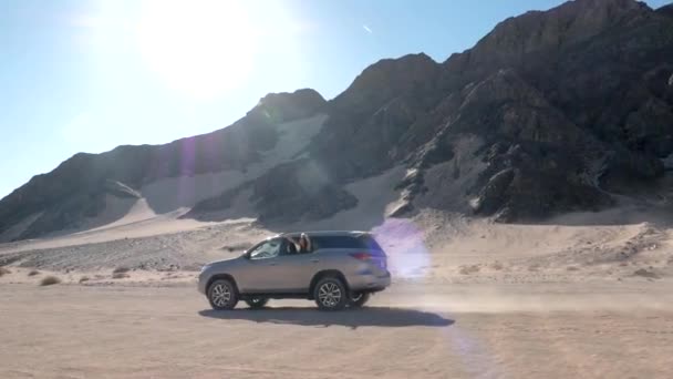 Джип Современный Автомобиль Проезжает Через Долину Холмы Пустыне Солнцем Позади — стоковое видео