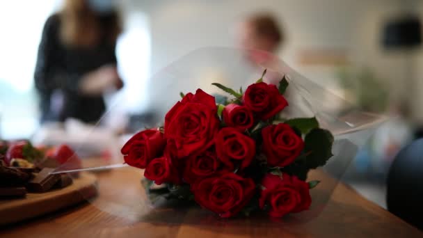 Rote Rosen Blumenstrauß Plastik Gewickelt Auf Dem Tisch Menschen Reden — Stockvideo