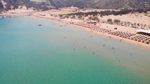 ギリシャのロードス島にあるツァンビカのプリスティンビーチで夏を楽しむ観光客 広い空中 — ストック動画