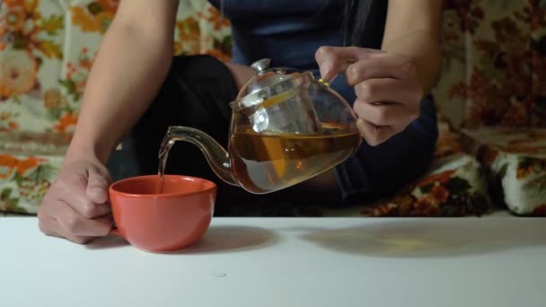 慢镜头 从透明玻璃茶壶到室内棕色茶杯的茶水 — 图库视频影像