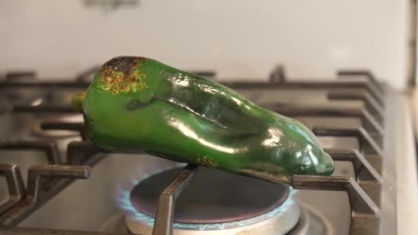 光沢のある濃い緑色のメキシコのポブラノペッパーが加熱し ストップトップのオープン炎の上に水ぶくれ この灼熱の方法は それを剥離することができることが重要です — ストック動画
