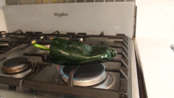 光沢のある濃い緑色のポブラノペッパーは まだ調理されていない ストーブの火の上に座っています すぐに それは明るく柔らかくなり始めます メキシコ料理の象徴的な食材です — ストック動画