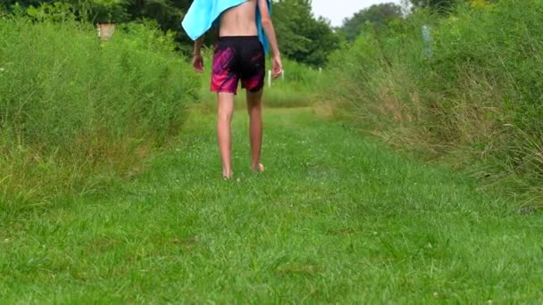 湖で泳いだ後 低木に囲まれたパスを歩いて背の高い男のショットを傾ける スローモーションショット — ストック動画