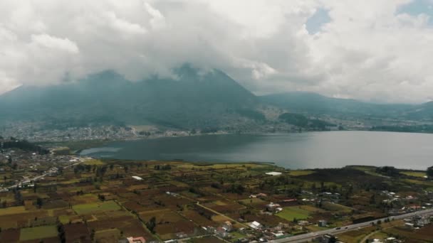 エクアドルのオタバロの農村部の町で前景にサンパブロ湖と雲の中にImbabura火山 幅広のドローン — ストック動画