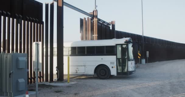 最近逮捕された移民を運ぶ米国政府バスは テキサス州ミッションの近くの米墨国境の壁の門を通過します — ストック動画