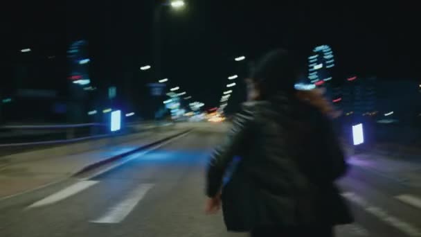 フード付きの女性が夜に通りを追いかけ カメラを振る — ストック動画