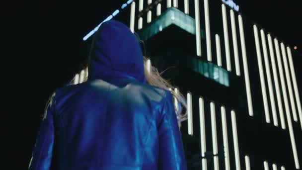 Μια Γυναίκα Κουκούλα Κοιτάζει Κτίριο Του Ουλεμίστε Νύχτα — Αρχείο Βίντεο