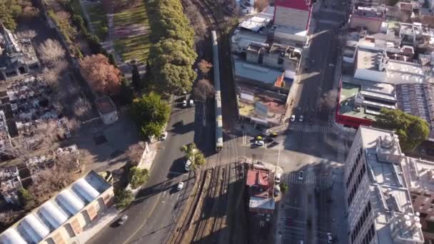 列車はブエノスアイレス墓地と共にアルゼンチンのチャカリタ駅まで走る鉄道路線を通過する 空中ドローン旋回ビュー — ストック動画