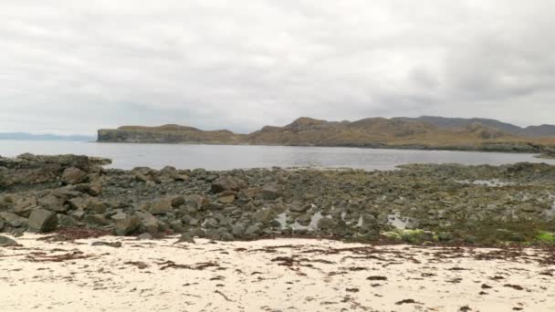 慢慢的侧向移动 潘宁沿着苏格兰的一个沙滩射击 俯瞰着岩石 背景中的海洋和山脉 苏格兰Ardnamurchan半岛 — 图库视频影像