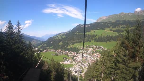 グリソンズ州のケーブルカーに乗る ゴンドラのリフトが谷に降ります 渓谷にある小さな村と ハイキングコースがあるスイスの美しい自然を見ることができます — ストック動画