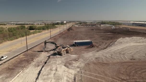 ダンプトラックとローダーによって掘削されている建設現場を通過する車 — ストック動画