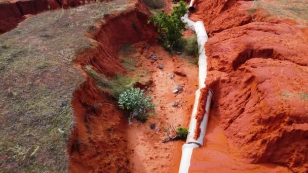 Tubería Agua Expuesta Suelo Rojo Debido Erosión Tiro Con Dron — Vídeo de stock