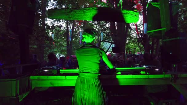 ヘッドフォンを持つアーティストは 音楽祭で働く女性Djの大群衆の前で演奏森の再生テクノで二重奏曲を書いた フィリップ マルニッツによる森の地下音楽パーティーでの撮影 — ストック動画