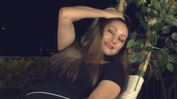 Γυναίκα Χαλαρώνοντας Μια Εξωτερική Κούνια Νύχτα Χαμόγελα Καθώς Γέρνει Προς — Αρχείο Βίντεο
