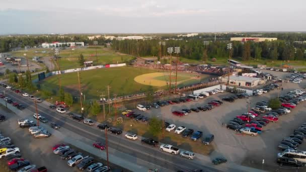 夏の最長の日にアラスカのフェアバンクスで真夜中の太陽クラシック野球の試合中に成長した記念フィールドで駐車場の4Kドローンビデオ — ストック動画
