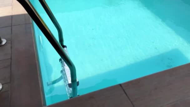 はしご付きのスイミングプールでクリスタルクリアターコイズブルーの水 遅い移動高角度ショット — ストック動画