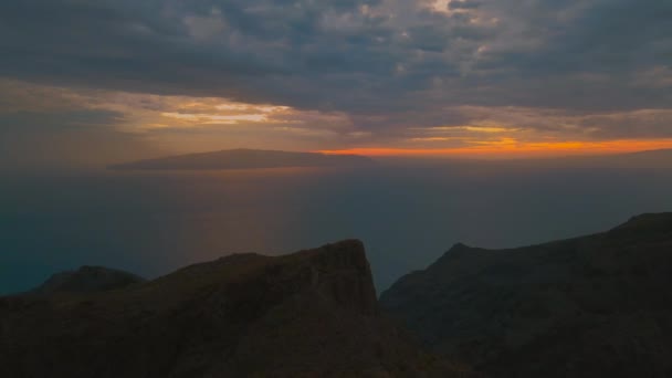 山のシルエットで水の上に沈む夕日のカラフルなショットを魅了する空の側と美しい雲の形成には 夕暮れのドローンショット — ストック動画