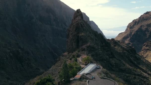 Dolly Aérea Hacia Roca Puntiaguda Gigante Con Pequeña Aldea Montañosa — Vídeo de stock