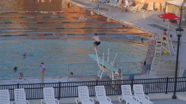 コロラド州グレンウッドスプリングスの温泉プールでダイビングボードから飛び降りる白人の少年 スローモーション — ストック動画