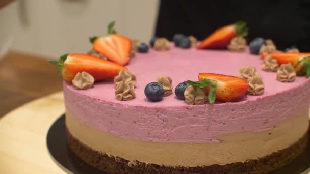 ベリーでクリームケーキを飾る女性 お祝いのためにおいしいクリーミーなケーキにブルーベリーを置く菓子の女性のクローズアップ — ストック動画