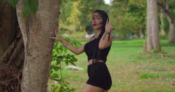 Yüzü Boyalı Genç Bir Kadın Tropikal Bir Parkta Saçlarıyla Oynuyor — Stok video