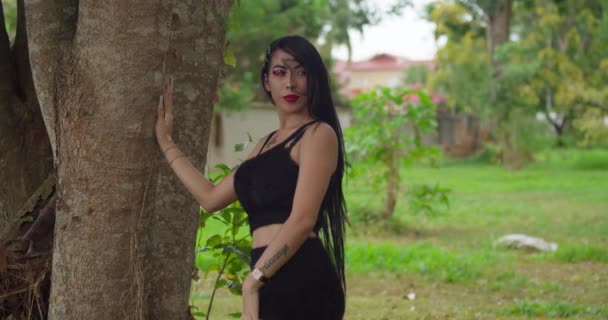 公園の設定で木の横に立って黒で素晴らしい若いラティーナ — ストック動画
