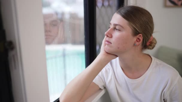 Junge Kaukasierin Sitzt Und Schaut Aus Dem Spiegelnden Fenster Hause — Stockvideo