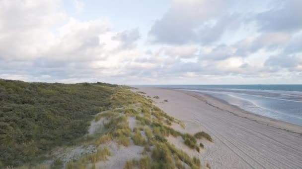 オランダのビーチと北の海の青い水の横に遅い空飛ぶサングラス砂丘 — ストック動画
