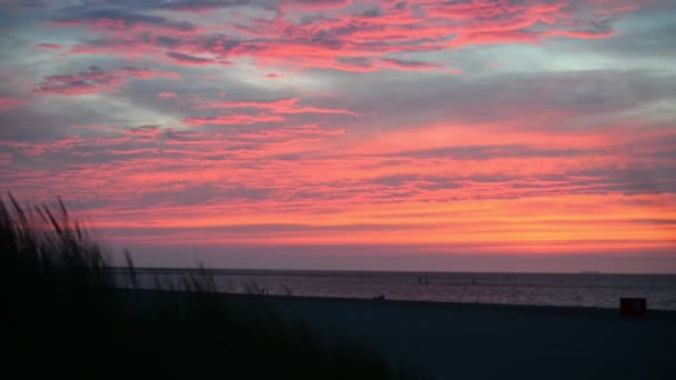 北の海でのビーチでの極端なオレンジ色の曇りの夕日のワイドショット — ストック動画