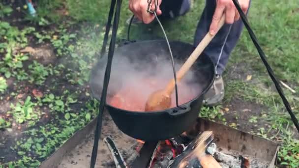木の火の上で一時停止 または釜で調理ガラス料理を攪拌男 — ストック動画