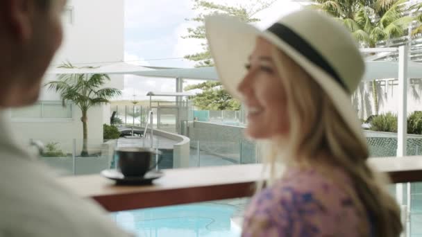 男性と一緒にコーヒーを持っている白人女性の笑顔プールビューカフェスローモーションで — ストック動画