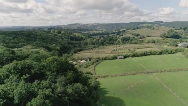 美しい夏の緑のデヴォンの風景の上に広い空中追跡 グラミング小屋と 前景にユルト イギリスのデヴォン — ストック動画